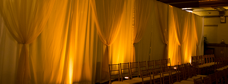White Poly-Premier drape with Sheer Champagne Gathers for a wedding at the Hotel John Marshall. Uplights add an amber glow to the look.