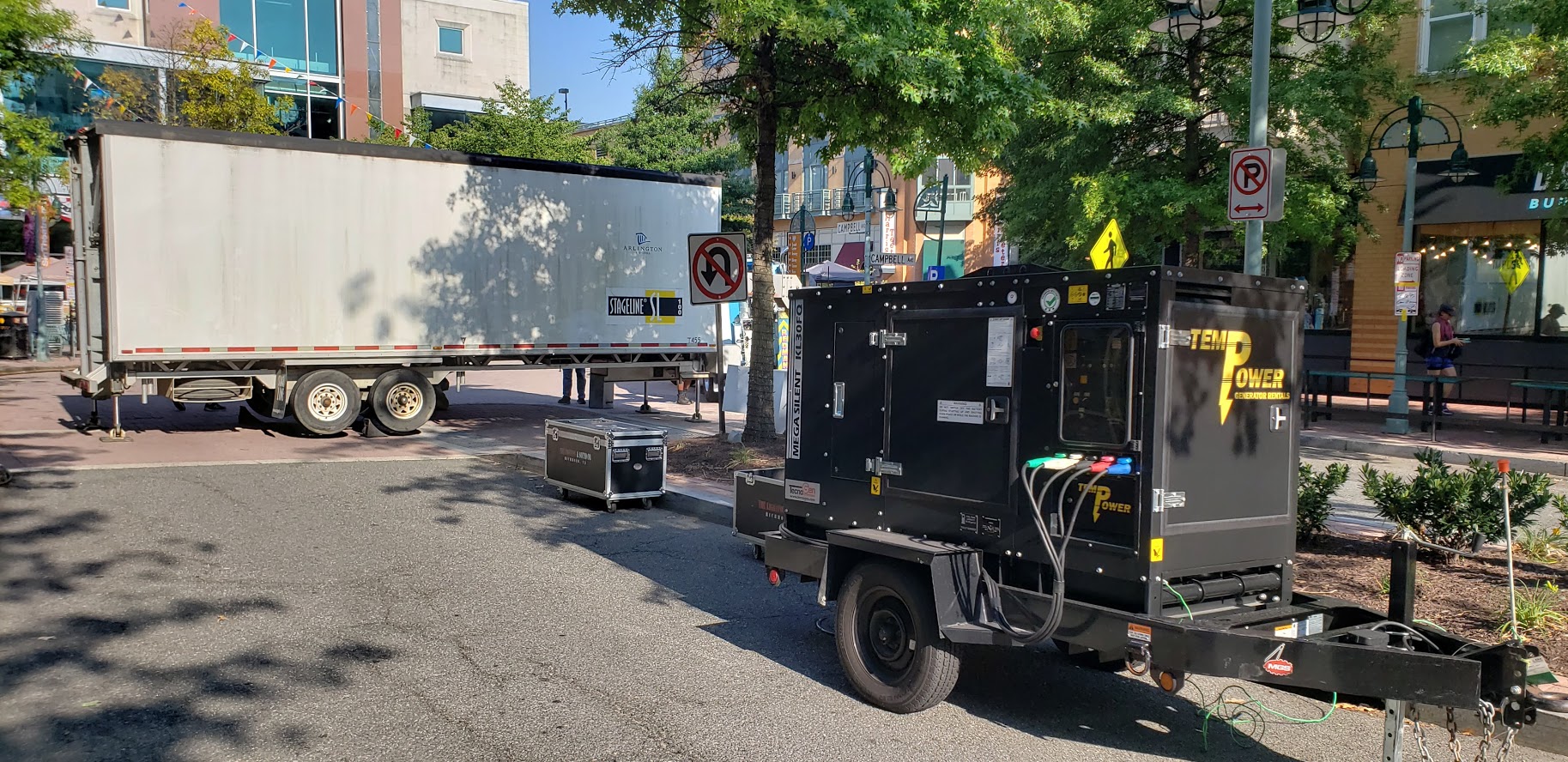 A portable quiet-run generator and mobile stage are set up for an event