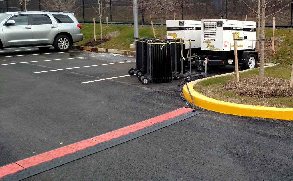 Generators provide power for a special event. Cords cross a roadway inside cable ramps protected from vehicle traffic